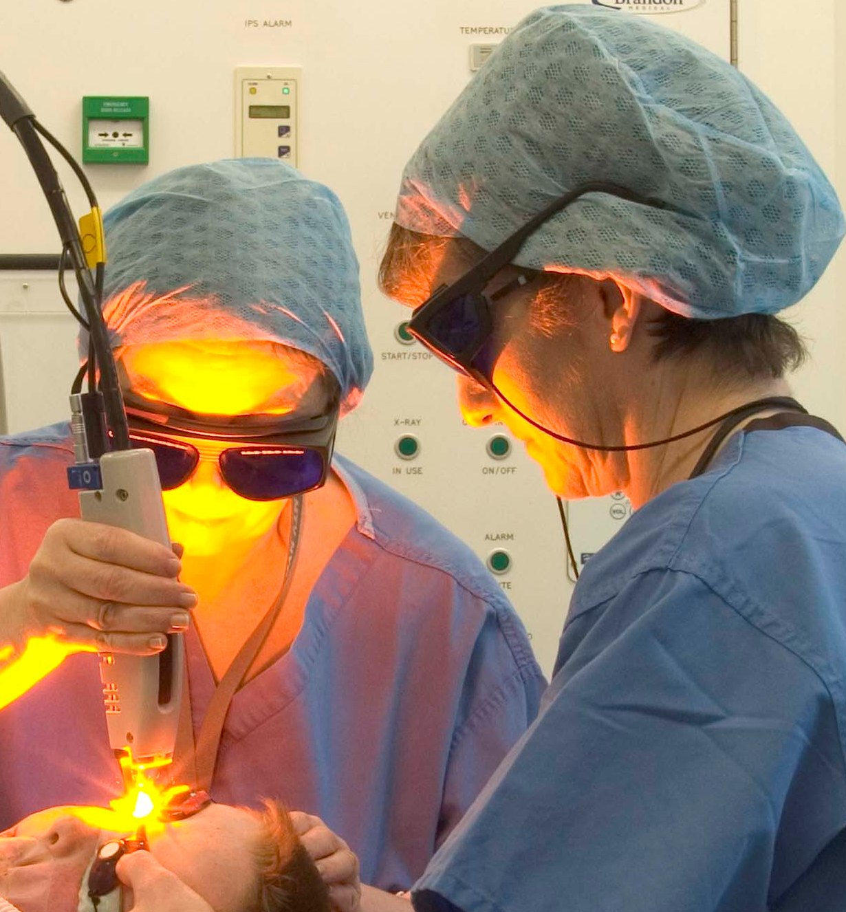 Two doctors performing a laser treatment on a person