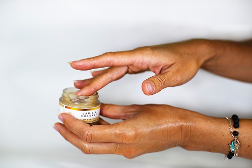 A woman dipping her finger into a lotion container