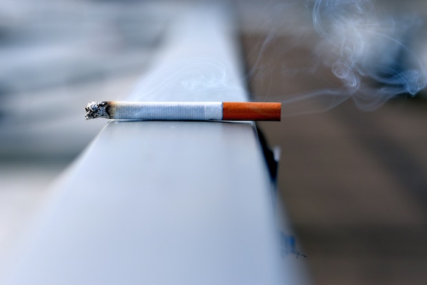 A lit cigarette resting on a wall